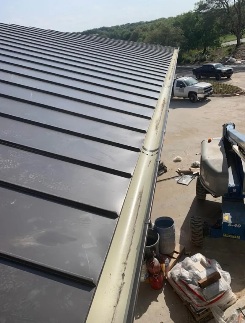 Standing seam panel and gutter detail on a metal roofing jobsite in Ozark